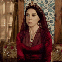 a woman in a red dress with a necklace and a tiara on her head
