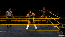 two wrestlers are in a ring with a referee and the word next on the ring