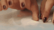 a close up of a woman 's hands with brown nail polish .