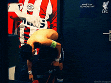a shirtless soccer player with the number 3 on his shorts is standing in front of a sign that says home team technical staff