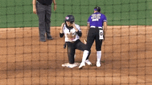 a baseball player with the number 32 on her jersey is kneeling on the ground