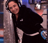 a woman wearing headphones and a puma sweatshirt is standing in a room .
