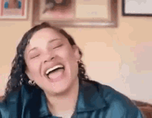a woman is laughing with her eyes closed and her tongue out while sitting on a couch .