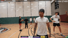 a man in a white shirt stands on a basketball court watching a game between max & ray and random3