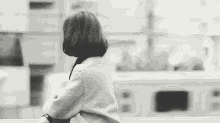 a black and white photo of a woman in a coat sitting on a railing .