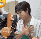 a person with their hands on their chest and a sticker that says tung behind them
