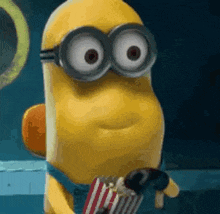 a minion wearing goggles is holding a bag of popcorn and a marshmallow .