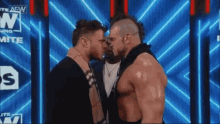 two wrestlers are standing next to each other and looking at each other .