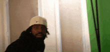 a man in a white hat is standing in front of a green screen .