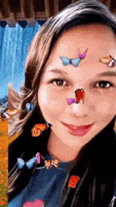 a girl with butterflies on her face is smiling in front of a waterfall