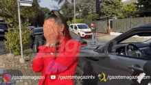 a woman in a red jacket is covering her face in front of a car and a sign that says gazetemagazin