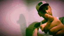 a man wearing a baseball cap is pointing at the camera