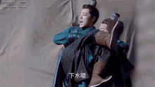 a man is carrying another man in his arms with chinese writing on the ground