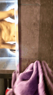 a purple towel hangs on a wall next to a naked man