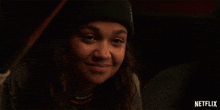 a close up of a woman wearing a beanie and smiling .