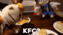 two stuffed animals are sitting at a table with a plate of food and the word kfc written on it