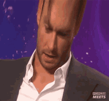 a man in a suit and white shirt is on a pop buzz meets screen