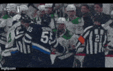 a group of hockey players are fighting on the ice .