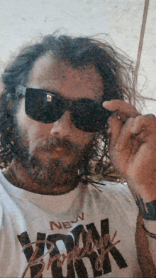 a man wearing sunglasses and a white shirt that says new york