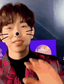 a young man is wearing a cat mask on his face and waving at the camera .