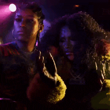 two women are standing next to each other in a dark room with purple lights .