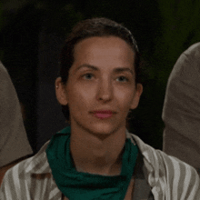a woman wearing a green scarf around her neck and a striped shirt .