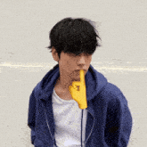 a man wearing a blue hoodie has a yellow finger on his mouth