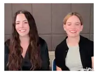 two women are sitting next to each other and smiling at the camera .