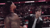a man in a leather jacket is standing in a wrestling ring