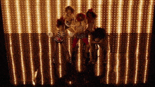 a group of women are dancing in front of a wall with lights on it