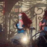 a woman in a blue top is kneeling down on a stage with a man playing a guitar
