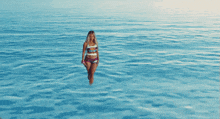 a woman in a bikini is walking in the water