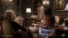 a group of people are sitting in a living room with a man standing behind them .
