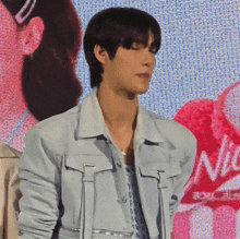 a man wearing a light blue jacket stands in front of a screen that says nice
