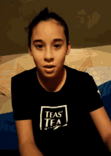 a young girl wearing a black teas tea t-shirt