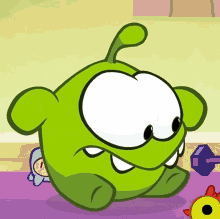 a green cartoon character is sitting on a purple rug