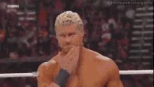 a wrestler is covering his mouth with his hand during a wrestling match .