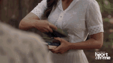 a woman in a white dress is holding a stack of books with the words super channel heart & me on the bottom right
