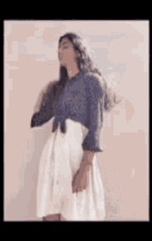 a woman is wearing a blue shirt and a white skirt .