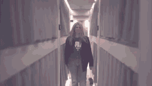 a woman walking down a hallway wearing a shirt that says " er you "