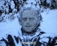 a man with ice on his face is standing in the snow .