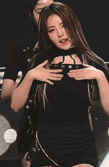 a woman making a heart shape with her hands while another woman looks on