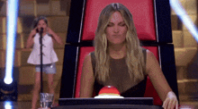 a woman is sitting in a chair with a red button on her desk