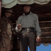 two men standing next to each other one of whom is holding a revolver