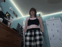 a woman wearing a black crop top and plaid pants