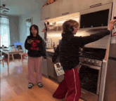 two people in a kitchen with one wearing a sweatshirt that says nys. jd.