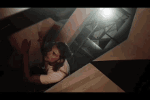 a man in a white shirt is looking up at something in a dark room