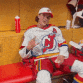 a man in a jersey with the letter j on it is sitting on a bench