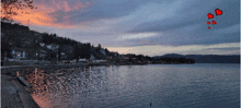 a sunset over a lake with a few hearts in the sky