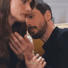 a man with a beard is kissing a woman 's hand .